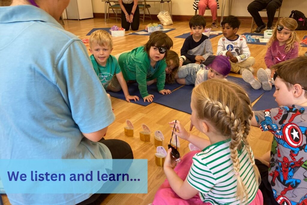 the children watch as the teacher shows them a number exercise